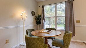A dining area with a round wooden table, four upholstered chairs, a floor lamp, and a window with curtains. - The Mulberry: huge yard full kitchen 32 minutes to the beach (North Charleston)