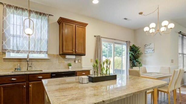 A kitchen with wooden cabinets, a granite countertop, and a dining area with a table and chairs. - The Mulberry: huge yard full kitchen 32 minutes to the beach (North Charleston)
