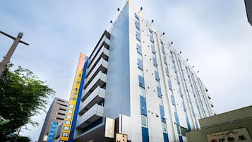 A multi-story building with a modern architectural design, featuring a prominent vertical sign with text.