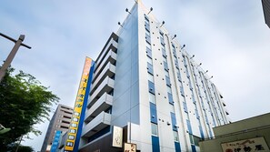 A multi-story building with a modern architectural design, featuring a prominent vertical sign with text. - Super Hotel Mito Natural Onsen (Mito)