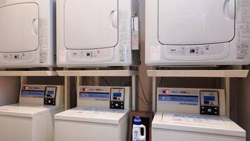 A laundry facility with multiple washing machines and dryers, each with control panels and digital displays.