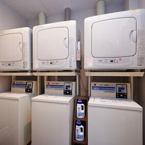 A laundry facility with multiple washing machines and dryers, each with control panels and digital displays. - Super Hotel Mito Natural Onsen (Mito)