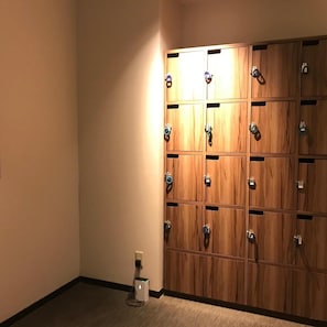 Una hilera de taquillas de madera con manijas metálicas, un enchufe en el suelo y un accesorio de luz fijado a la pared.
