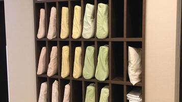 A storage unit with shelves containing folded blankets and pillows in various colors.