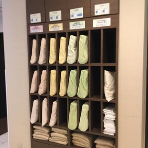 A storage unit with shelves containing folded blankets and pillows in various colors. - Super Hotel Mito Natural Onsen (Mito)