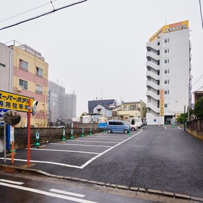 Un estacionamiento con autos, un edificio con un letrero y una calle.
