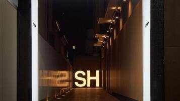 The entrance to a hotel with a prominent 'SUPER HOTEL' sign and a large illuminated 'SH' sign.