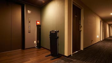 A hotel corridor with a carpeted floor, a trash bin, and doors leading to rooms.