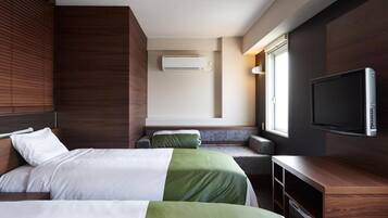 A hotel room with two beds, a TV, an air conditioning unit, and a window.