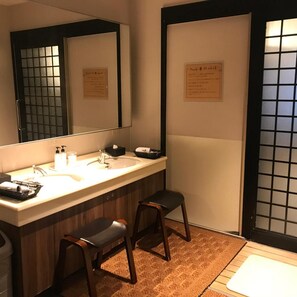 A bathroom with a large mirror, two sinks, a towel rack, and a small stool. - Super Hotel Mito Natural Onsen (Mito)