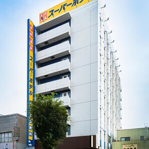 A multi-story building with a prominent yellow sign on the facade. - Super Hotel Mito Natural Onsen (Mito)