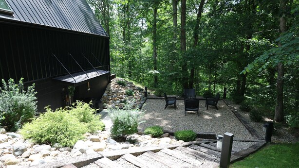 A wooden deck with a stone pathway leading to a seating area with benches. - Creative Cabins - The Frame (Logan)