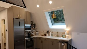 A modern kitchen with a skylight, stainless steel appliances, and a clean layout. - Creative Cabins - The Frame (Logan)