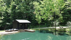 A cabin with a dock extending into a pond, surrounded by dense trees. - Creative Cabins - The Frame (Logan)