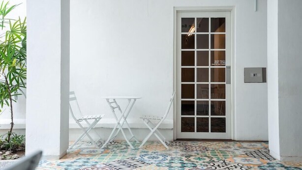 A room with a tiled floor, a white door with glass panels, a small white table, and a white chair. - Bobobox Pods Kota Lama Semarang (Semarang)