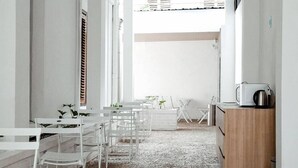 A narrow hallway with white furniture, a small table with plants, and a microwave on a cabinet. - Bobobox Pods Kota Lama Semarang (Semarang)
