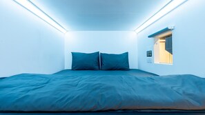 Un dormitorio pequeño y moderno con una cama, dos almohadas y una ventana con vistas.