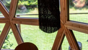 Een houten tafel met een theepot en een rekenraam, een hanglamp en uitzicht door grote ramen.