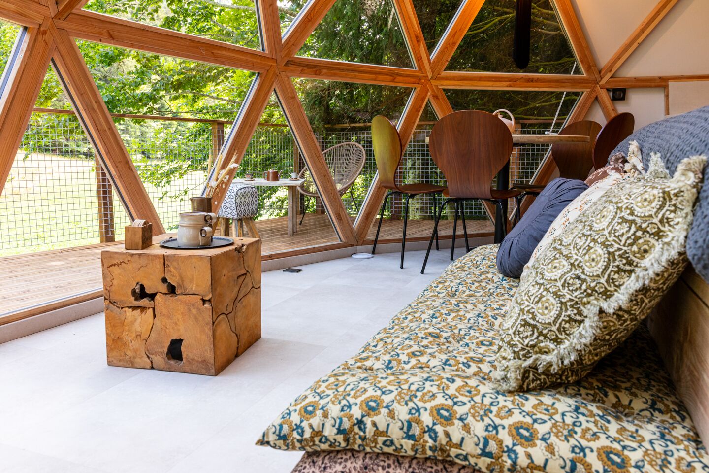 Un intérieur chaleureux avec une table basse en bois, un canapé à motifs et un coin repas comprenant des chaises et une table.