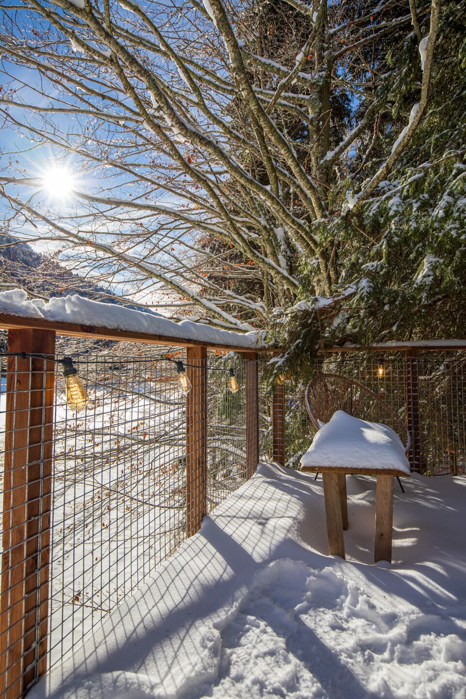 A snow-covered outdoor area with a wooden bench and a metal fence.