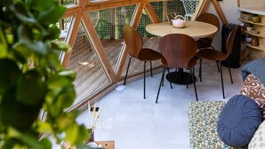 A room with a geometric wooden ceiling structure, a round wooden table with chairs, and a sofa with patterned cushions. - Comfortable panoramic dome in the heart of Vercors (Autrans-Méaudre-en-Vercors)