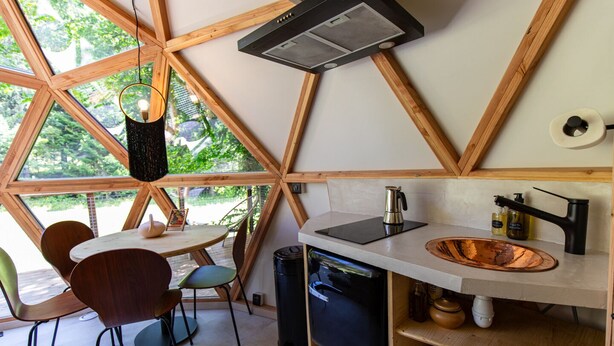 Een moderne keuken met een koperen spoelbak, een koffiezetapparaat en een zwarte afzuigkap.