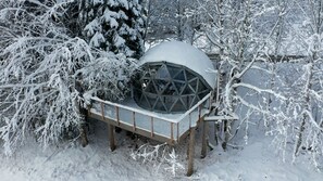 A snow-covered outdoor structure with a geometric glass dome, surrounded by snow-laden trees. - Comfortable panoramic dome in the heart of Vercors (Autrans-Méaudre-en-Vercors)