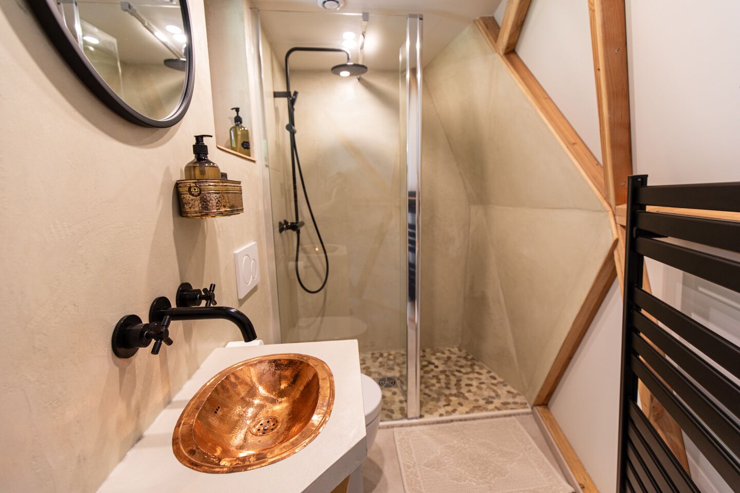 A bathroom with a copper sink, a shower, and a mirror.