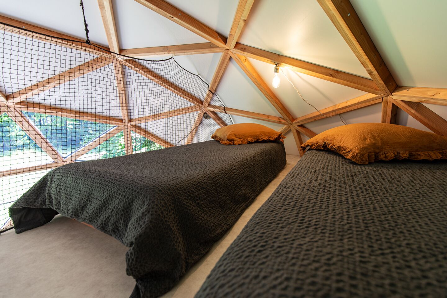 Een gezellige, driehoekige kamer met een bed en een raam met uitzicht op een natuurlandschap.