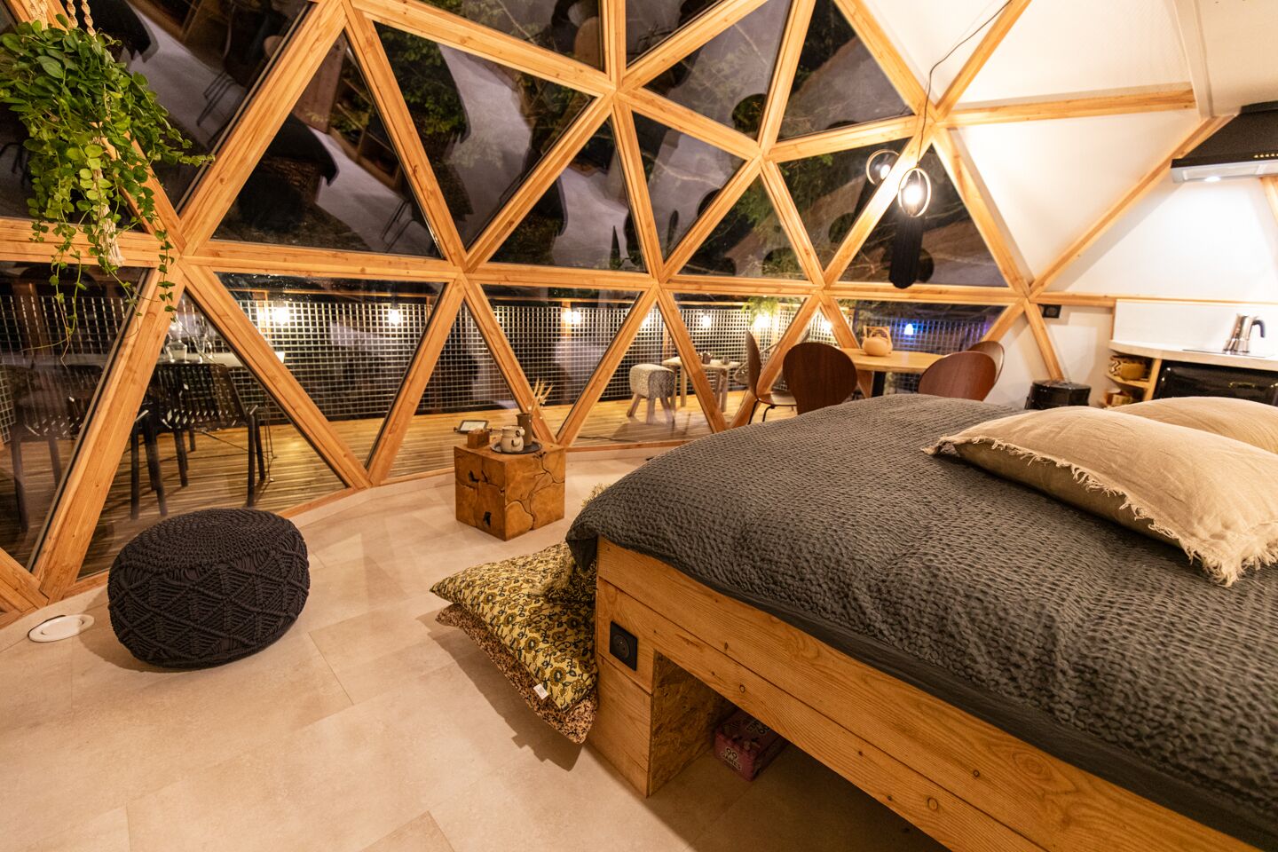 Une chambre confortable avec un lit en bois, un petit coin salon et une vue à travers une structure de fenêtre aux motifs géométriques.
