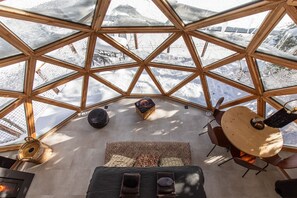 A geodesic dome structure with a view of snowy mountains. Inside, there is a seating area with a round table and chairs. - Comfortable panoramic dome in the heart of Vercors (Autrans-Méaudre-en-Vercors)