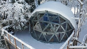 A snow-covered dome structure with a metal framework and a glass window, surrounded by snow-laden trees. - Comfortable panoramic dome in the heart of Vercors (Autrans-Méaudre-en-Vercors)