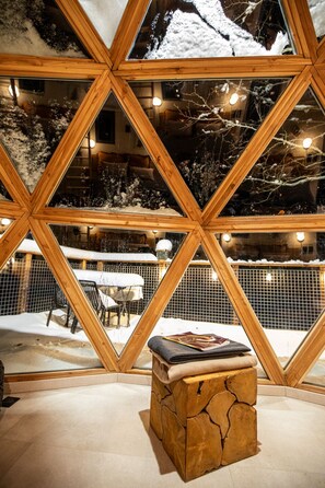 A snow-covered outdoor area with a wooden bench and a book, viewed through a geometric wooden structure. - Comfortable panoramic dome in the heart of Vercors (Autrans-Méaudre-en-Vercors)