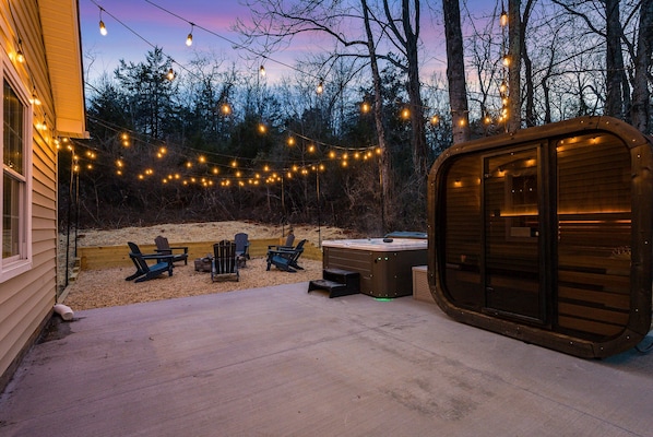 A wooden cabin with a hot tub, deck chairs, and string lights. - The Reserve at 151: Sauna, Hot Tub, Pool & Poker (Afton)