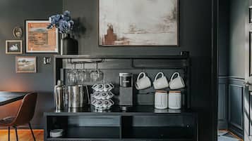Uma cozinha moderna com bancada preta, um espaço para café e um quadro com paisagem acima.