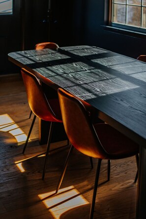 A dining table with a woven tablecloth, surrounded by four chairs with a metallic frame and a curved backrest.