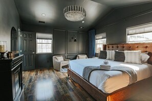 A modern bedroom with a large bed, a chandelier, and a view of the outdoors.