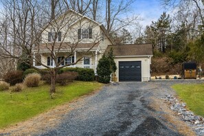 A two-story house with a front porch, a garage, and a gravel driveway.