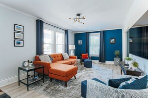 A modern living room with a sectional sofa, a patterned armchair, and a coffee table. - Cozy Craftsman: Newly Renovated/Downtown Staunton (Staunton)