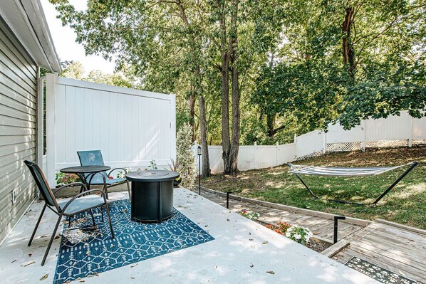 A patio area with a table and chairs, a hammock, and a covered seating area.