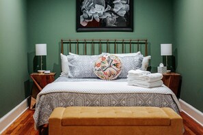A bedroom with a bed, two bedside tables, a nightstand, a bench, and a framed picture on the wall. - Shenandoah Valley Atelier: NEW Waynesboro Loft (Waynesboro)