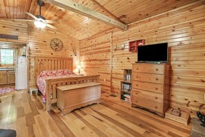 A wooden cabin room with a bed, a dresser, a television, and a ceiling fan. - Whip-poor-will Cabin | Hocking Hills, Firepit (Rockbridge)