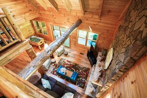 A cozy cabin interior with a wooden interior, a sofa, a coffee table, and a foosball table.