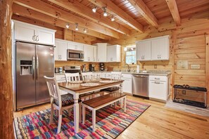 Una cucina con pareti in legno, mobili bianchi, elettrodomestici in acciaio inossidabile e un tappeto colorato.
