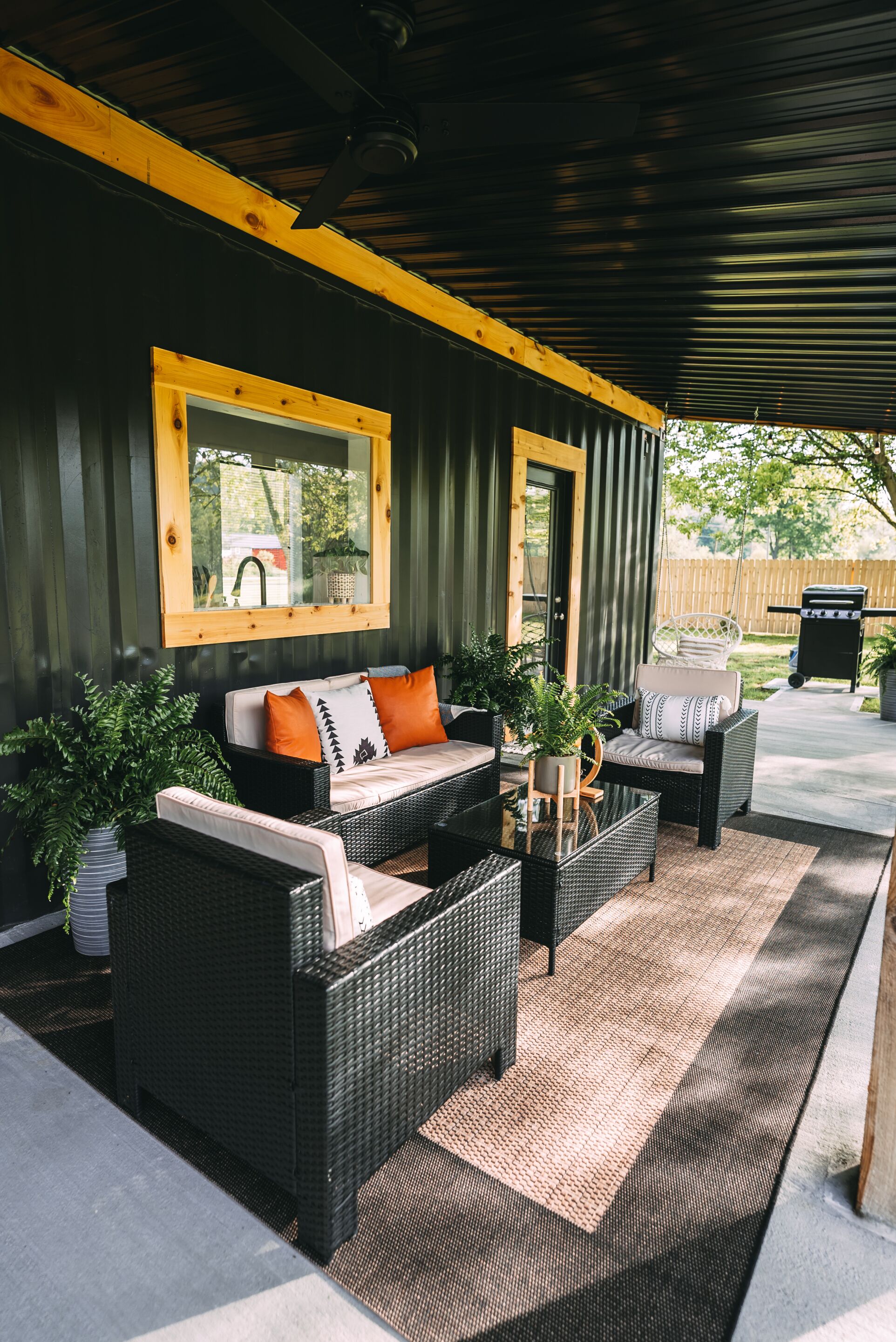 Un patio al aire libre con mobiliario de mimbre, una mesa con cubierta de vidrio y techo de madera.