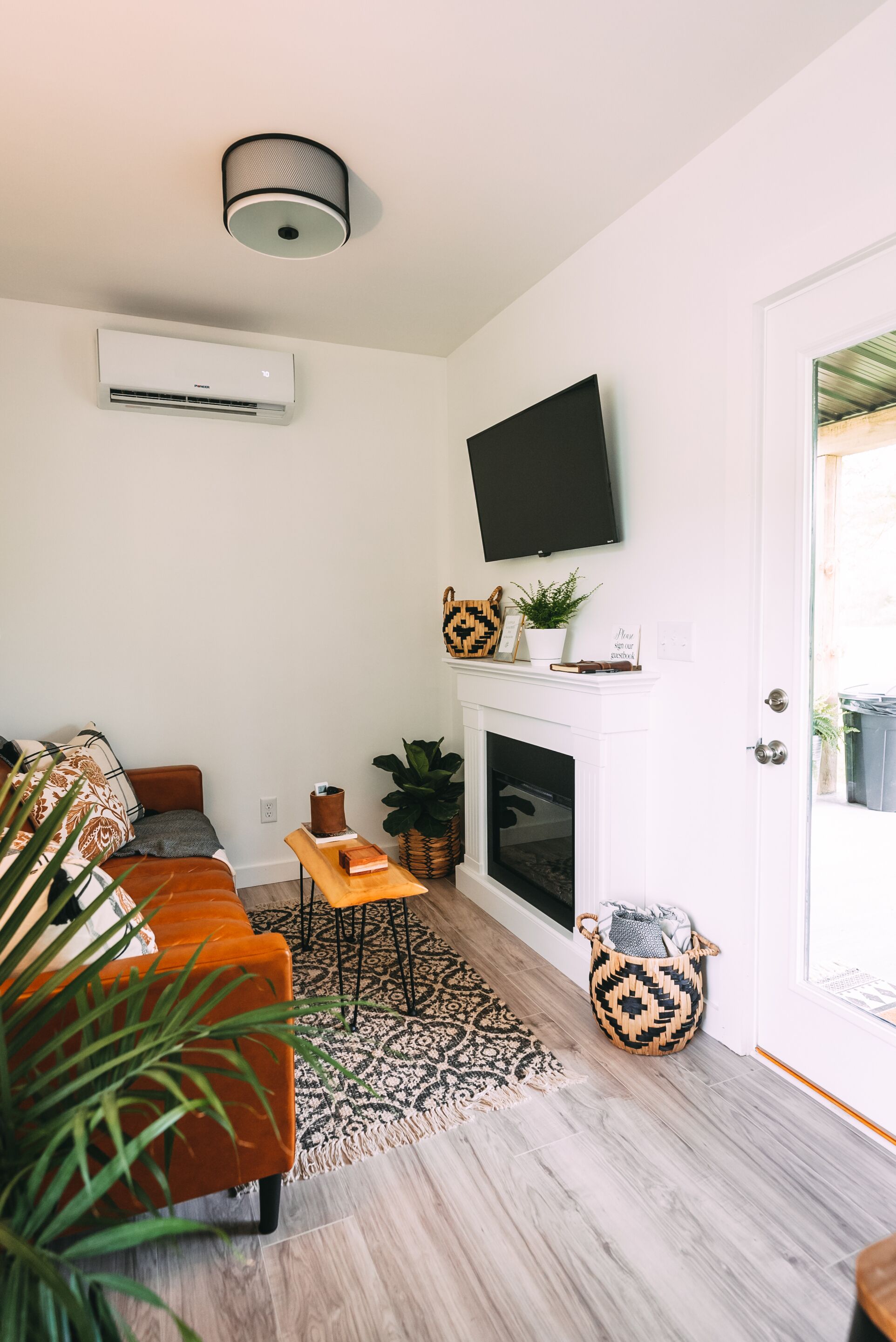 A living room with a sofa, a fireplace, a mounted television, and a door leading outside.
