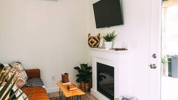 A living room with a sofa, a fireplace, a mounted television, and a door leading outside.