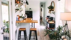 A modern kitchen with wooden countertops, a built-in oven, and a dining area with stools.