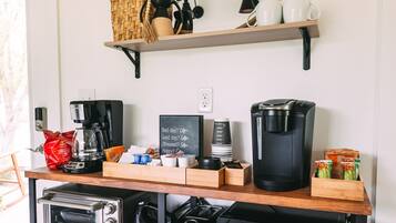 Una cocina con estación de café, microondas, tostadora y olla de cocción lenta.