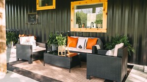 An outdoor seating area with wicker furniture, potted plants, and a wooden ceiling.